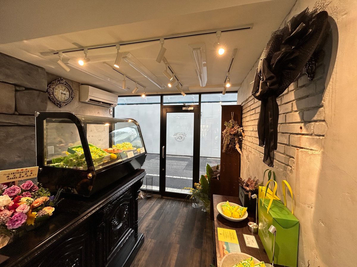 プレスリリースで公開されたパール洋菓子店 自由が丘の店内。黒いショーケースにレモンケーキが並び、白いレンガの壁と黄色い紙袋が見える