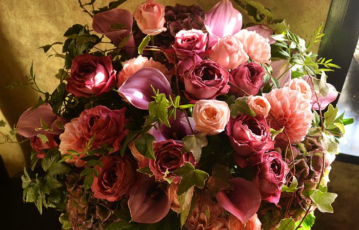 Fleuriste Charles Froment の公式サイトで公開された写真。濃淡のあるピンクと赤紫のバラを中心に、ほかの花と葉を合わせてこんもりと束ねたアレンジメント