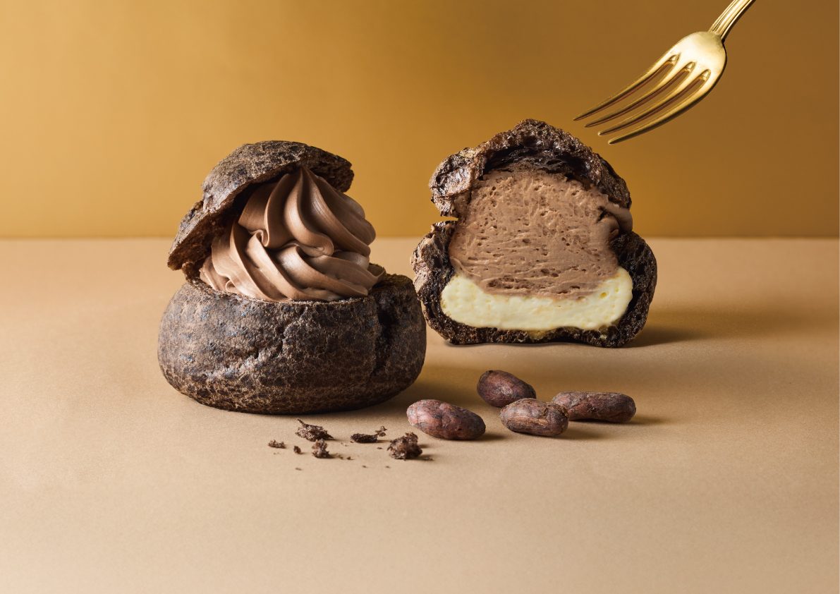 D'RENTY CHOCOLATE 公式サイトで公開されたシュークリーム。丸ごとのシューと断面が並び、断面からココア色の生地の中にホイップとカスタードが見える
