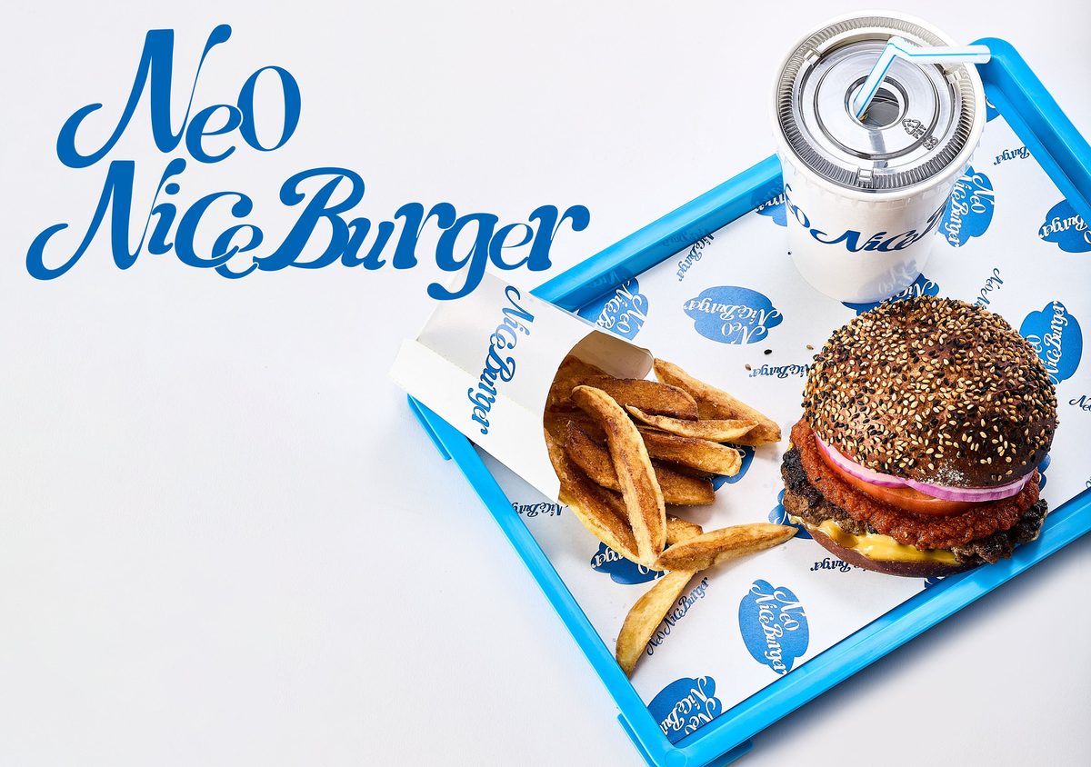 青いトレーに載った、ごまのバンズのハンバーガーとフライドポテト、紙カップの飲み物。左上に Neo Nice Burger のロゴ