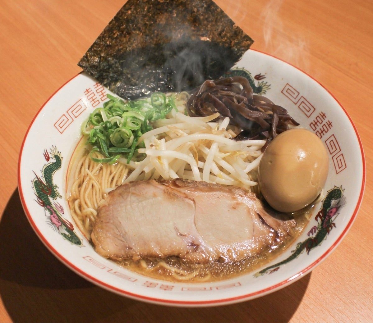 開店時のプレスリリースで公開されたらーめん。赤い縁取りの白い丼に、海苔、味付け玉子、チャーシュー、もやし、きくらげ、青ねぎがのる