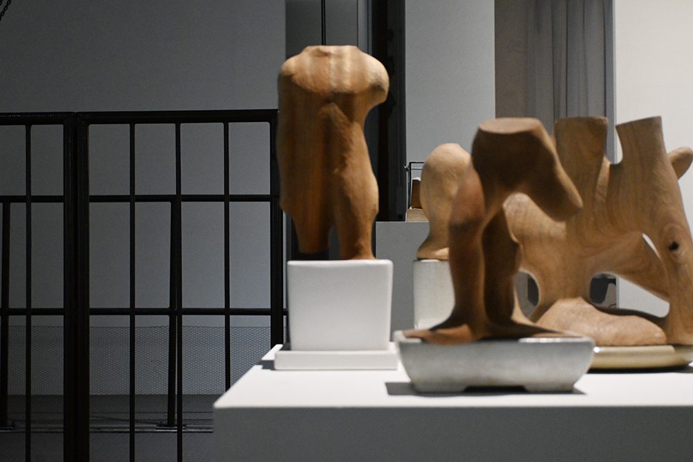 DIGINNER GALLERY の展覧会ページで公開された北山翔一の作品の展示風景。台座の上に頭部のないトルソー状の木彫と、鉢に据えられた木彫が並ぶ