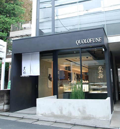 黒い庇に「QUOLOFUNE」と掲げた店舗の外観。左手に白い暖簾が下がり、右手はガラス張りのショーケース