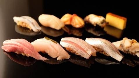 岡田不動産のプレスリリースで、よはくの紹介とともに公開された握りずしの写真。黒い台に握りが2列に並んでいる